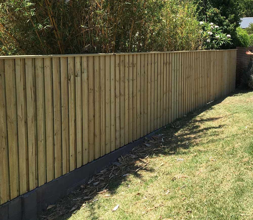 A Wooden Fence is Sitting on Top of a Lush Green Lawn — Rearden Fencing Pty Ltd in Toronto, NSW