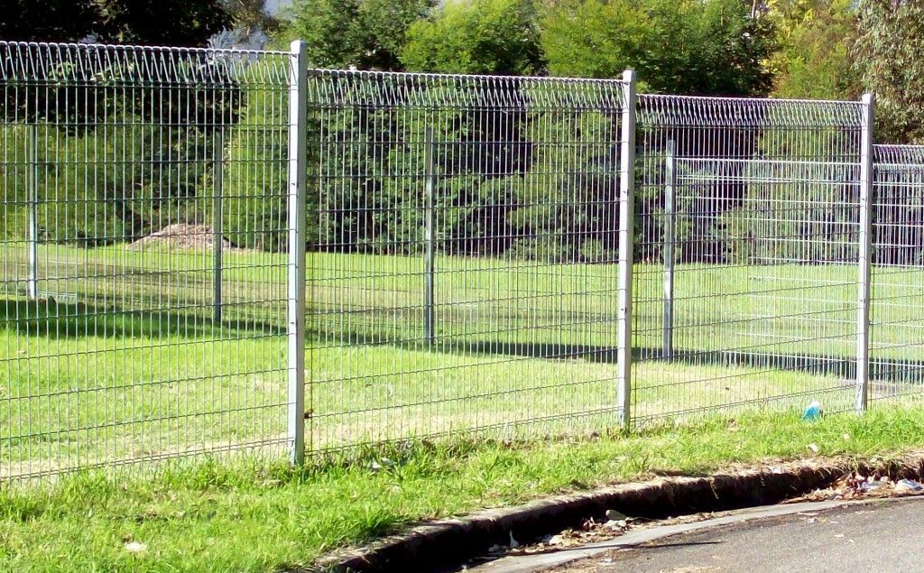 A Weldmesh Fence Is Surrounding a Field with Trees in The Background — Rearden Fencing Pty Ltd in Toronto, NSW