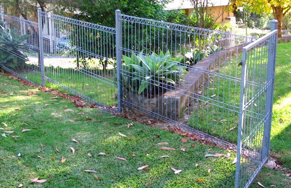 A Metal Fence is Surrounding a Lush Green Yard — Rearden Fencing Pty Ltd in Toronto, NSW