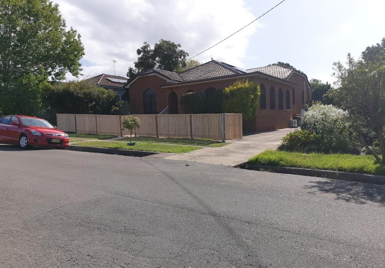 A Red Car Is Parked in Front of A House — Rearden Fencing Pty Ltd in Toronto, NSW