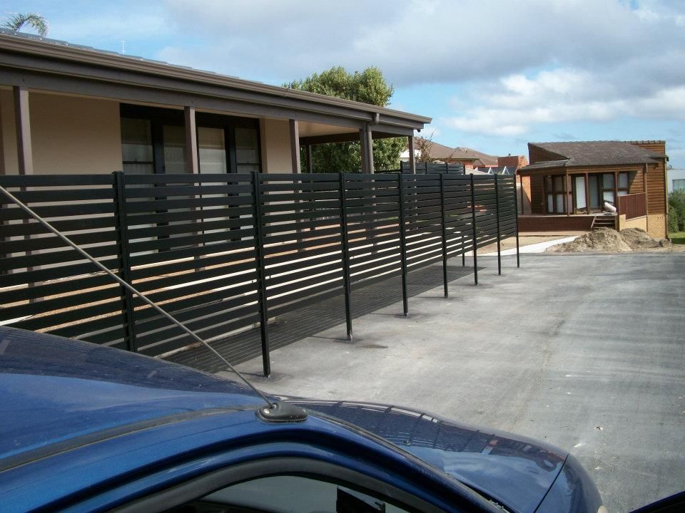 A Blue Car Is Parked in Front of A House with A Black Fence — Rearden Fencing Pty Ltd in Toronto, NSW
