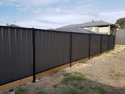 A Black Fence is in the Backyard of a House — Rearden Fencing Pty Ltd in Toronto, NSW