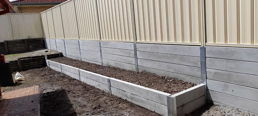 A Concrete Fence With a Planter in the Middle of It — Rearden Fencing Pty Ltd in Toronto, NSW