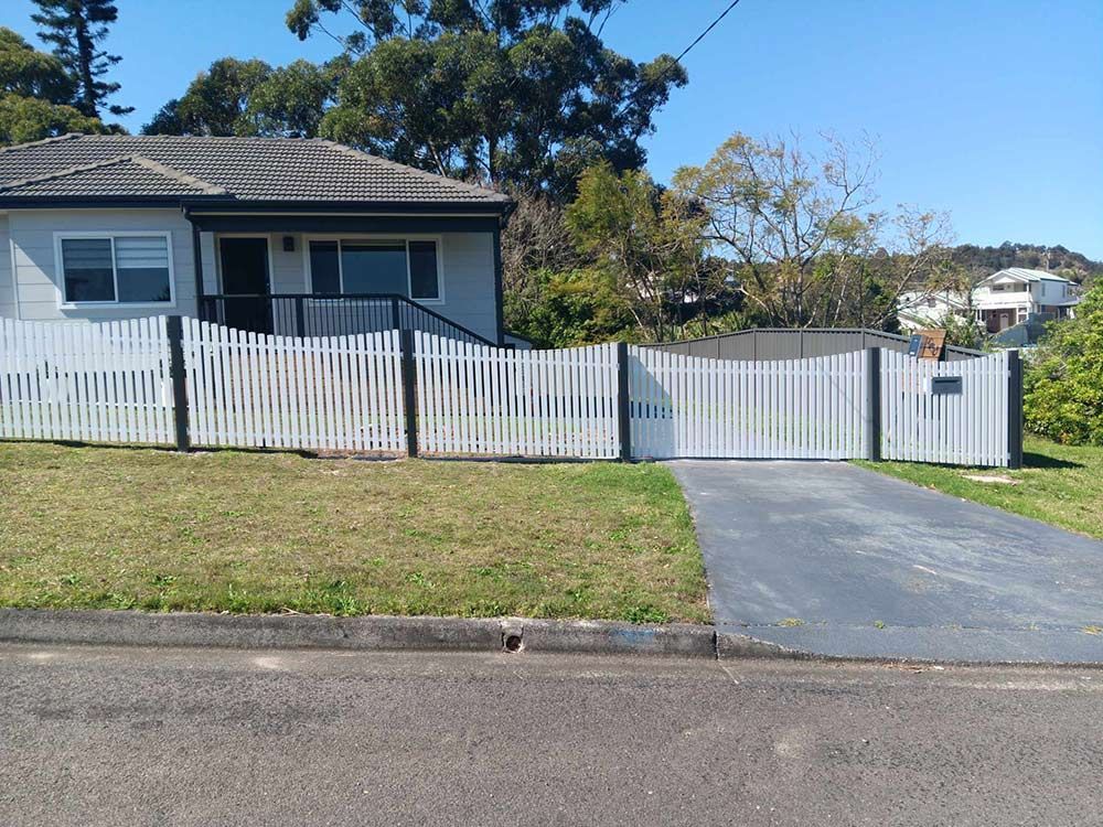 A House With a White Picket Fence and a Driveway — Rearden Fencing Pty Ltd in Toronto, NSW