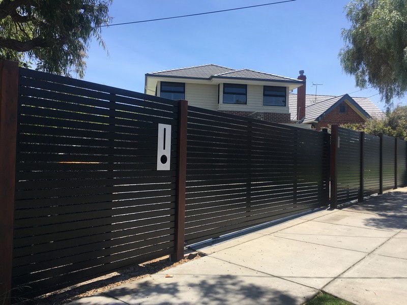 A Black Fence Surrounds a House on a Sunny Day — Rearden Fencing Pty Ltd in Toronto, NSW