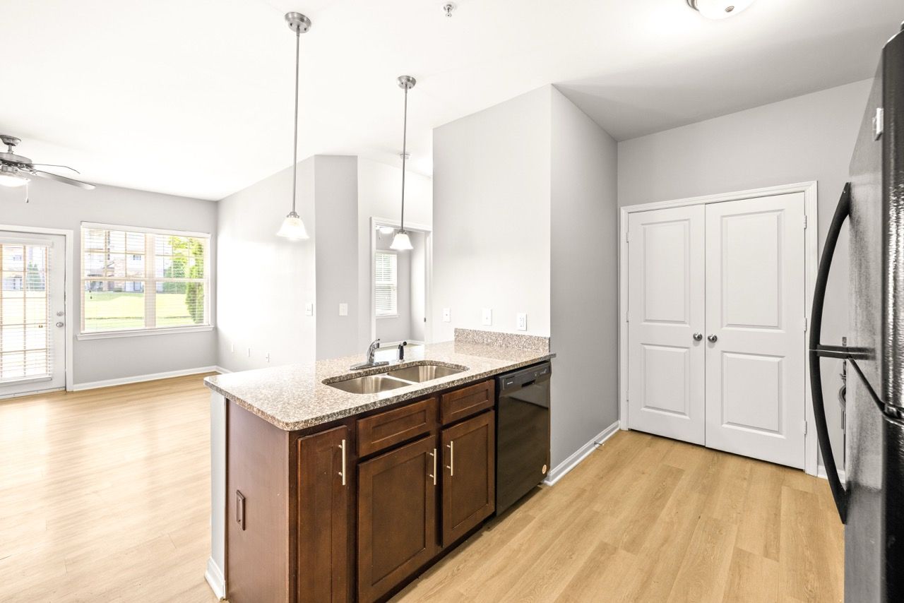 Open-concept kitchen with island, granite countertops, stainless steel appliances, and light wood flooring.