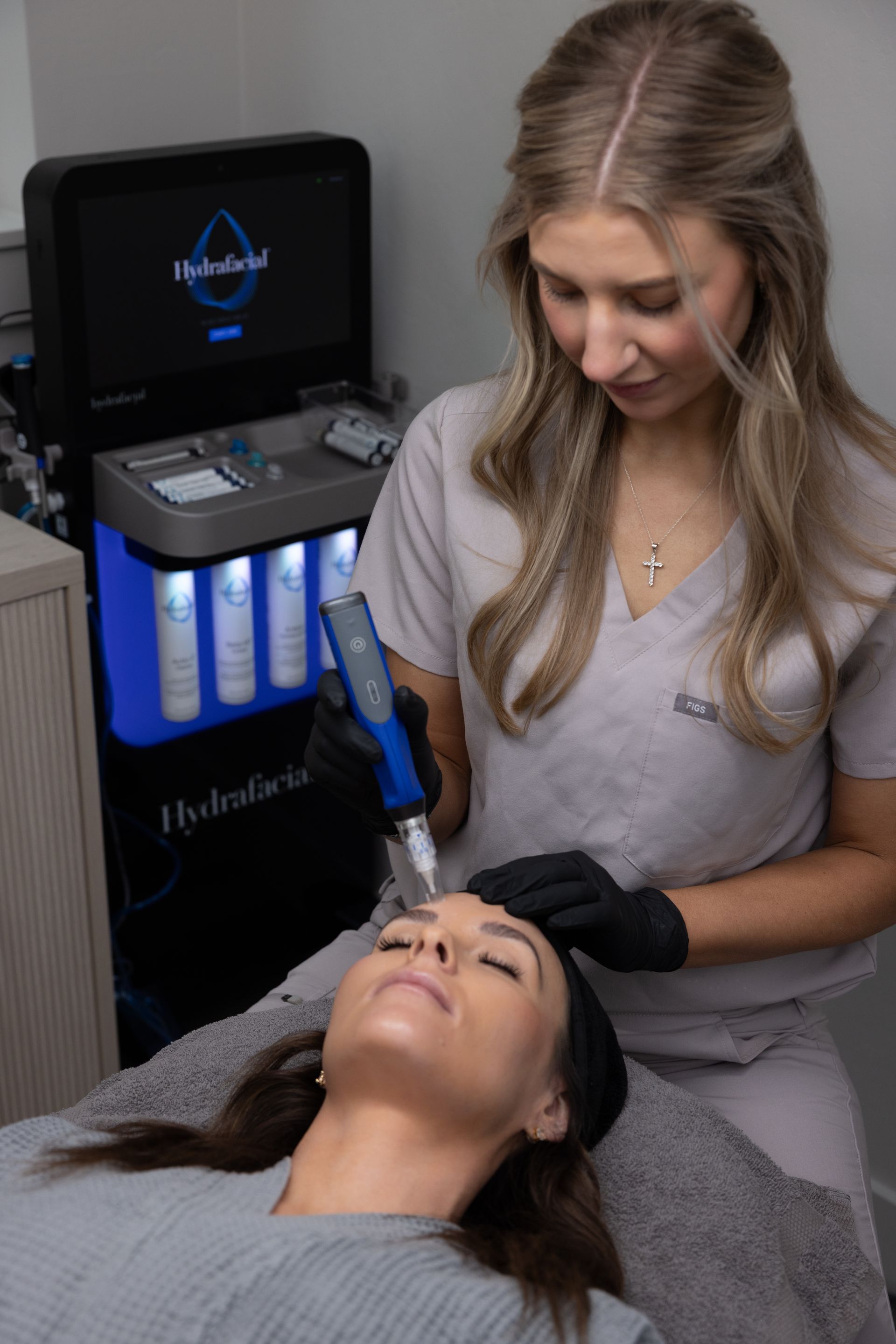 Woman receiving facial treatment from a spa device in a treatment room