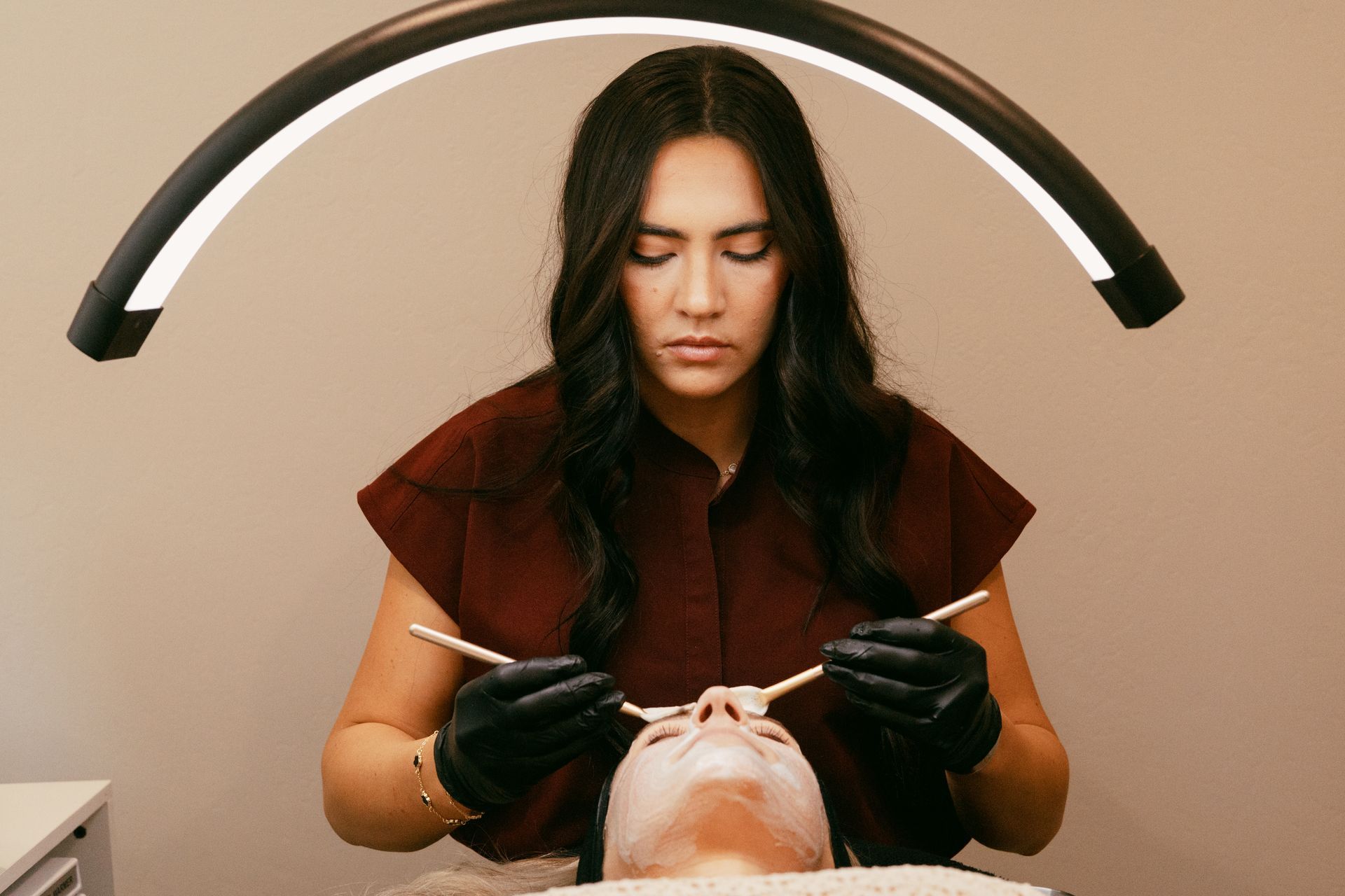 A woman is applying a mask to a man 's face.