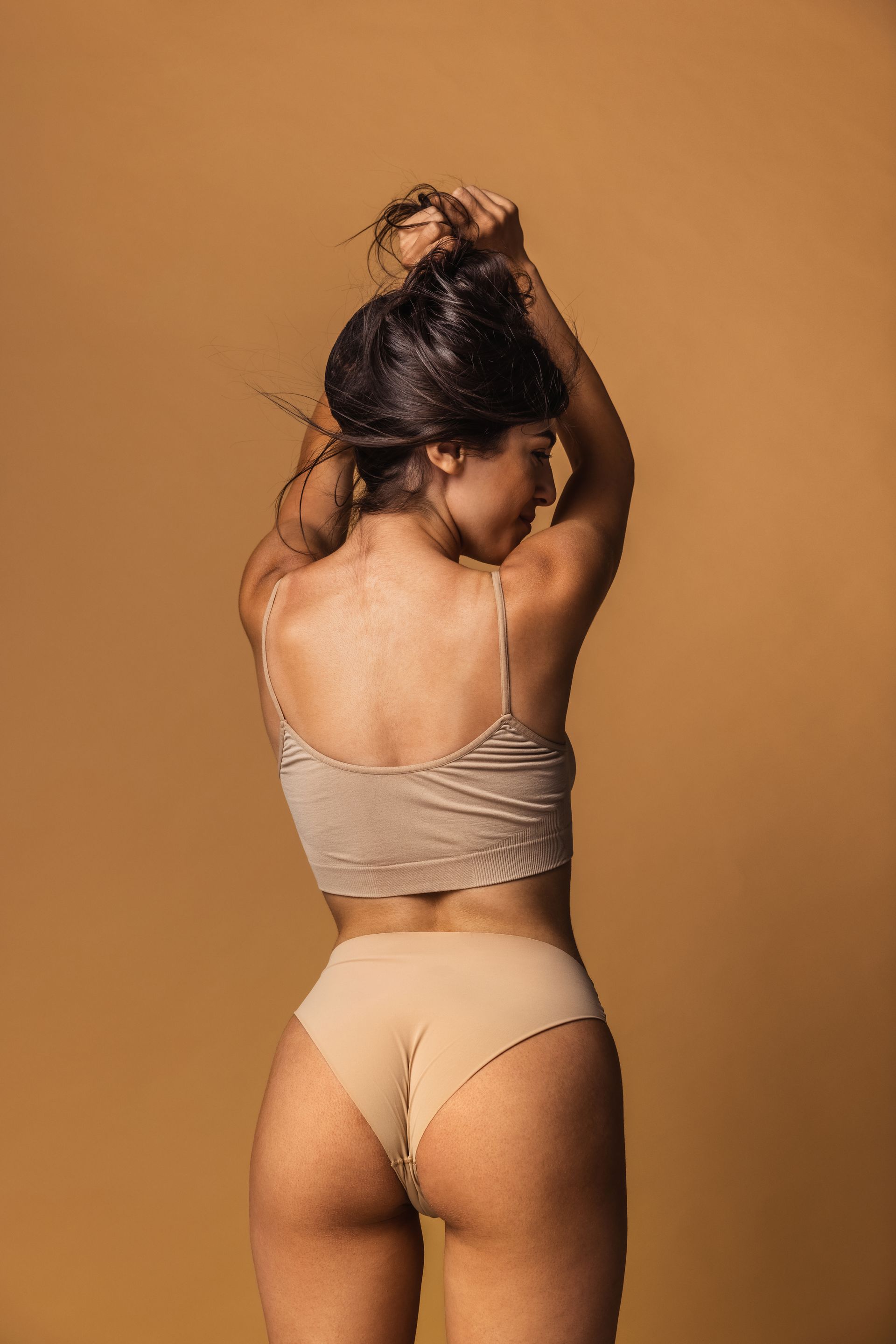 a woman in lingerie is standing on a white background .