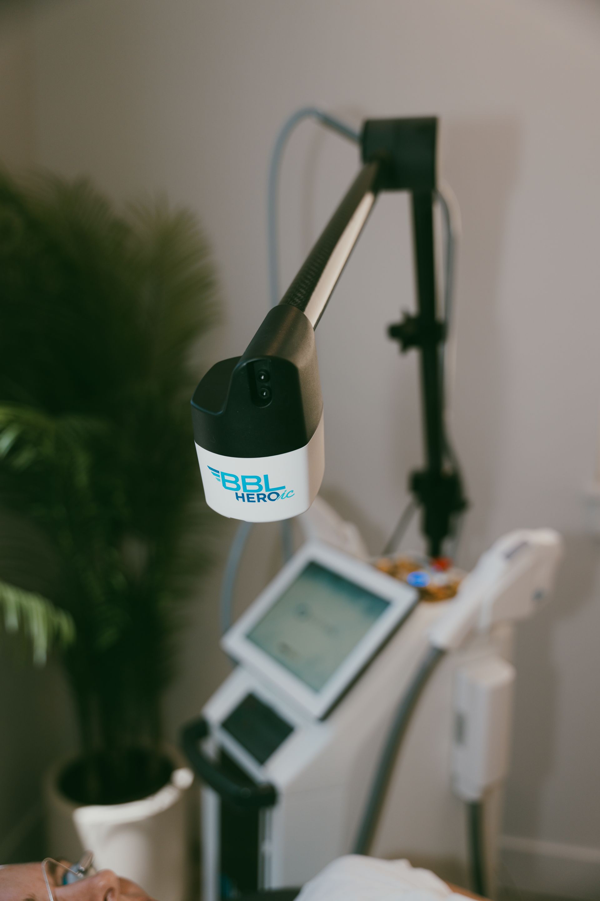 A medical device with a light applicator and a digital display. The device appears to be in a treatment room with a plant in the background.