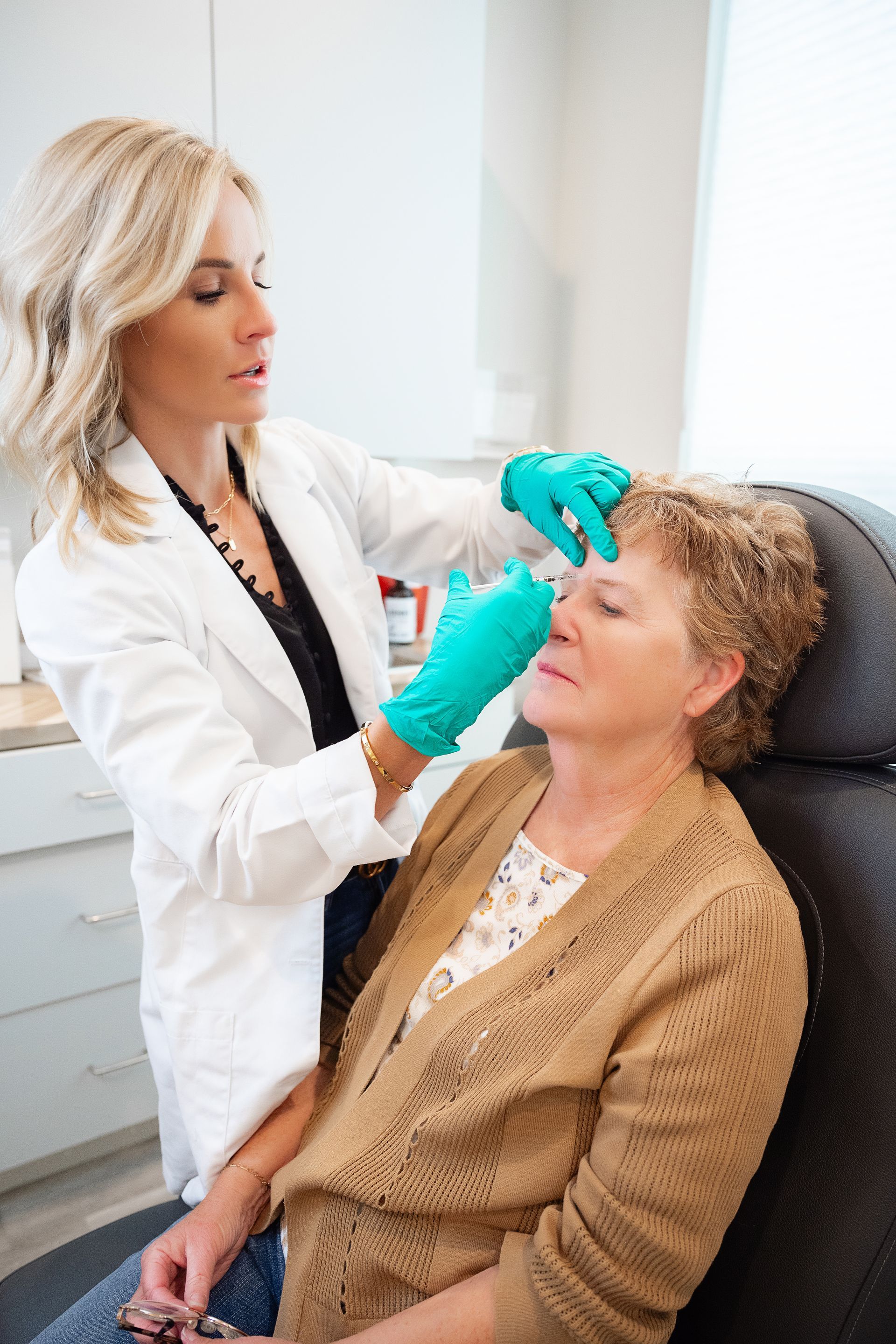 Doctor examining a patient’s face in a medical office, wearing teal gloves.