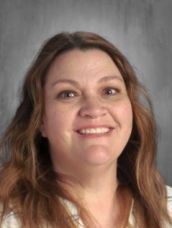 A woman with long brown hair is smiling for the camera.