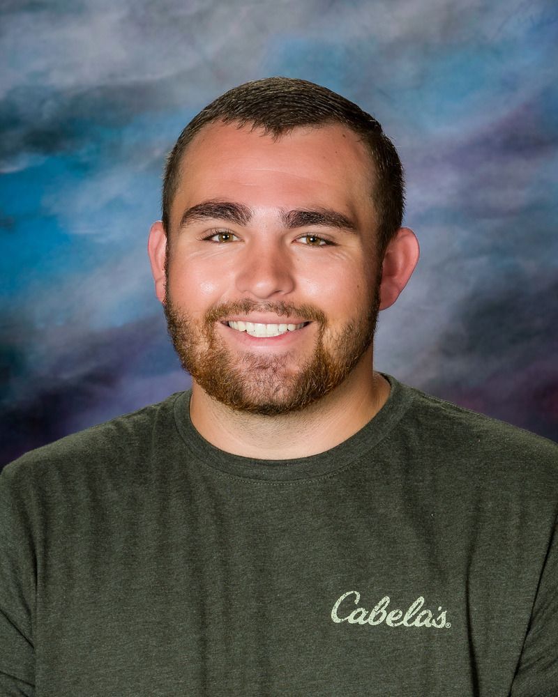 A man wearing a cabela 's shirt is smiling for the camera.