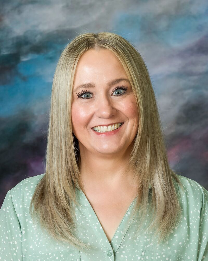 A woman in a green shirt is smiling for the camera.