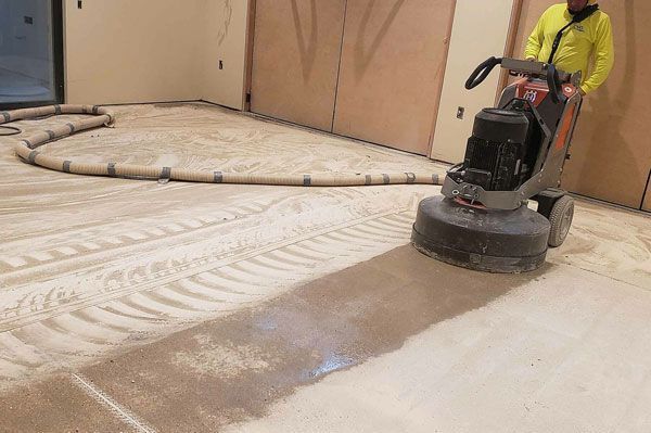 A man is grinding a concrete floor with a machine.