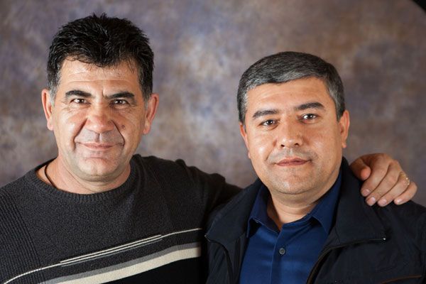 Two men are posing for a picture and one has his arm around the other 's shoulder