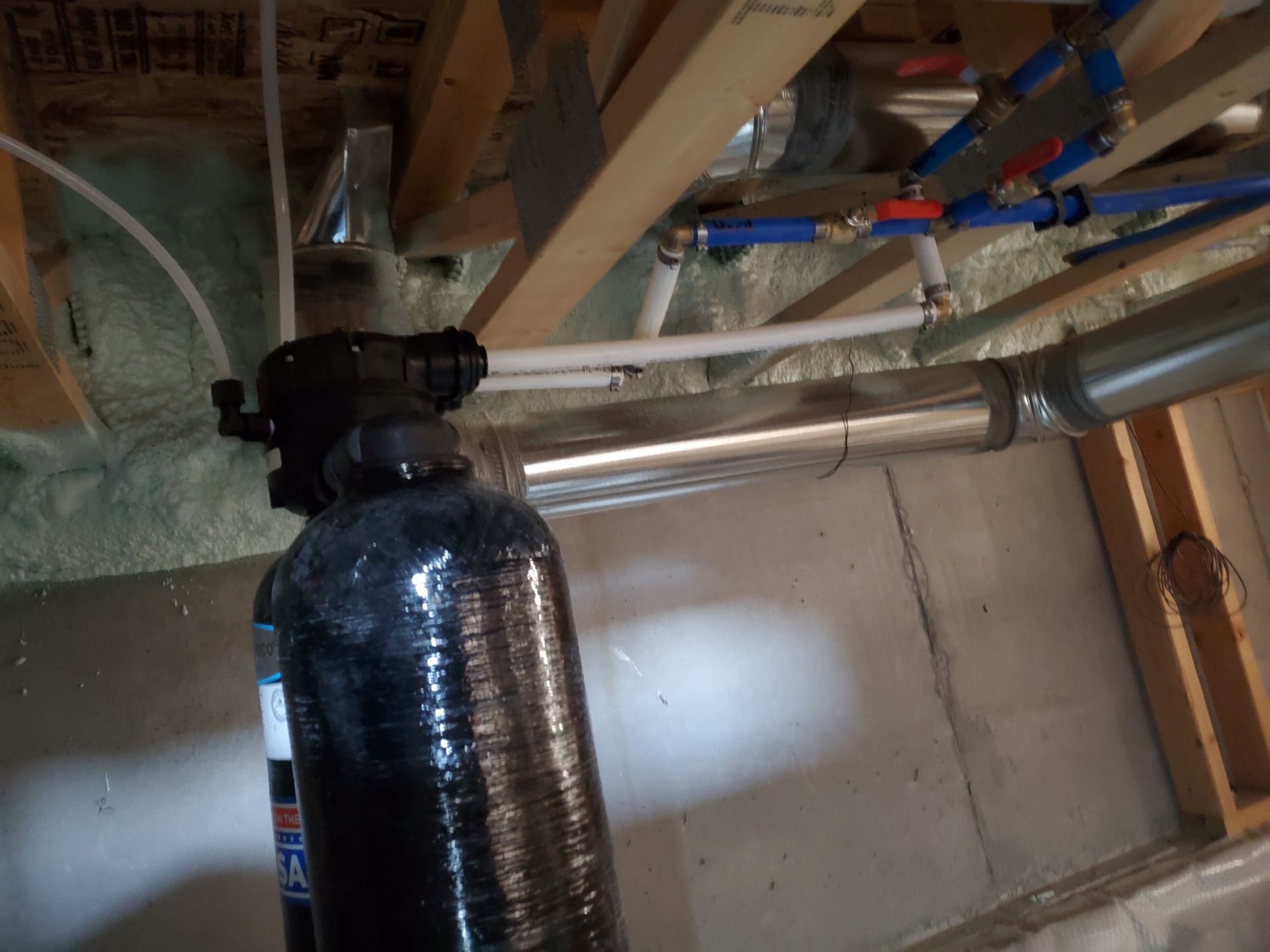 Black water filtration system installed in a basement, near ductwork and pipes.