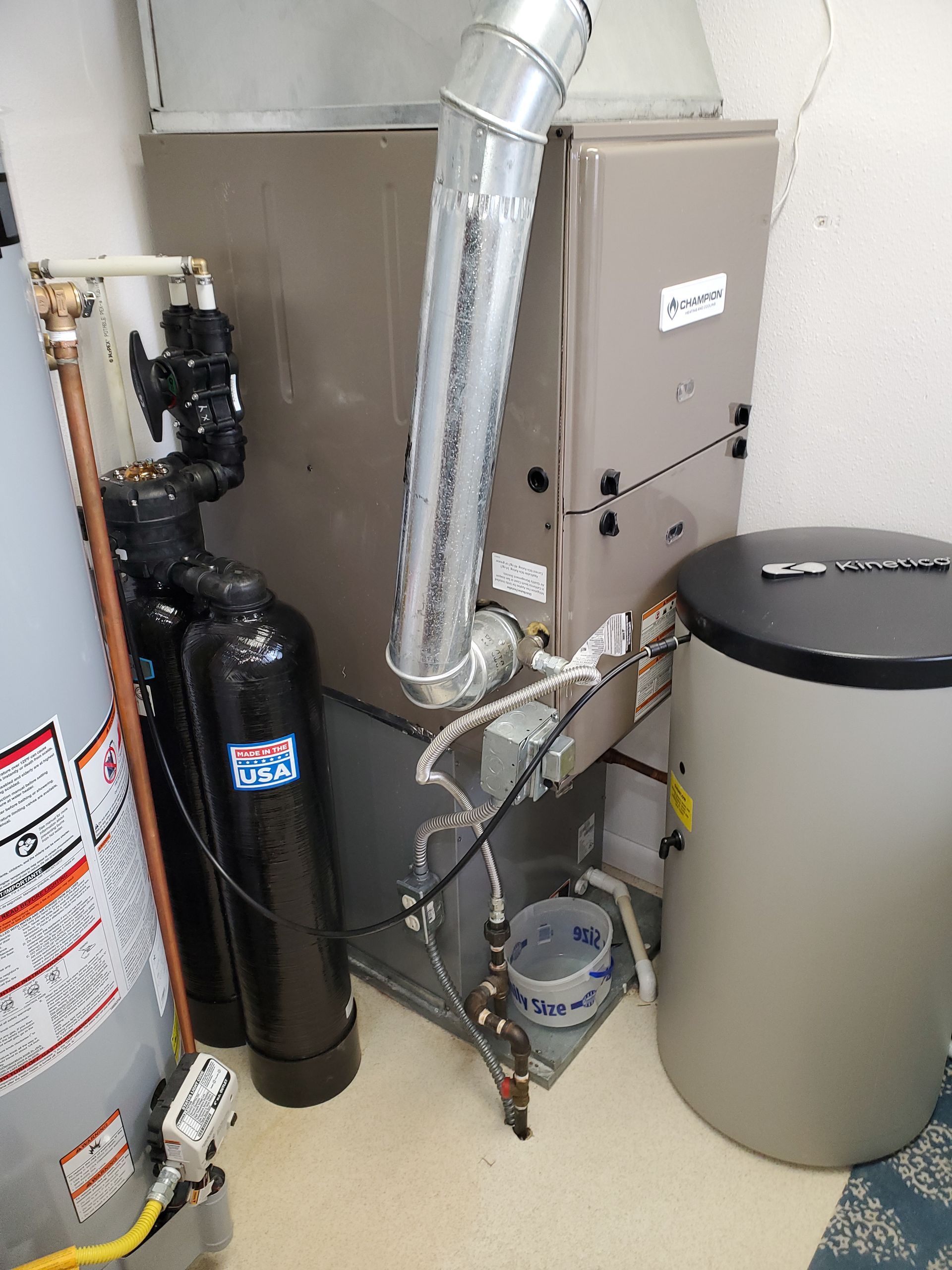 HVAC system next to water softener and water heater in a basement.
