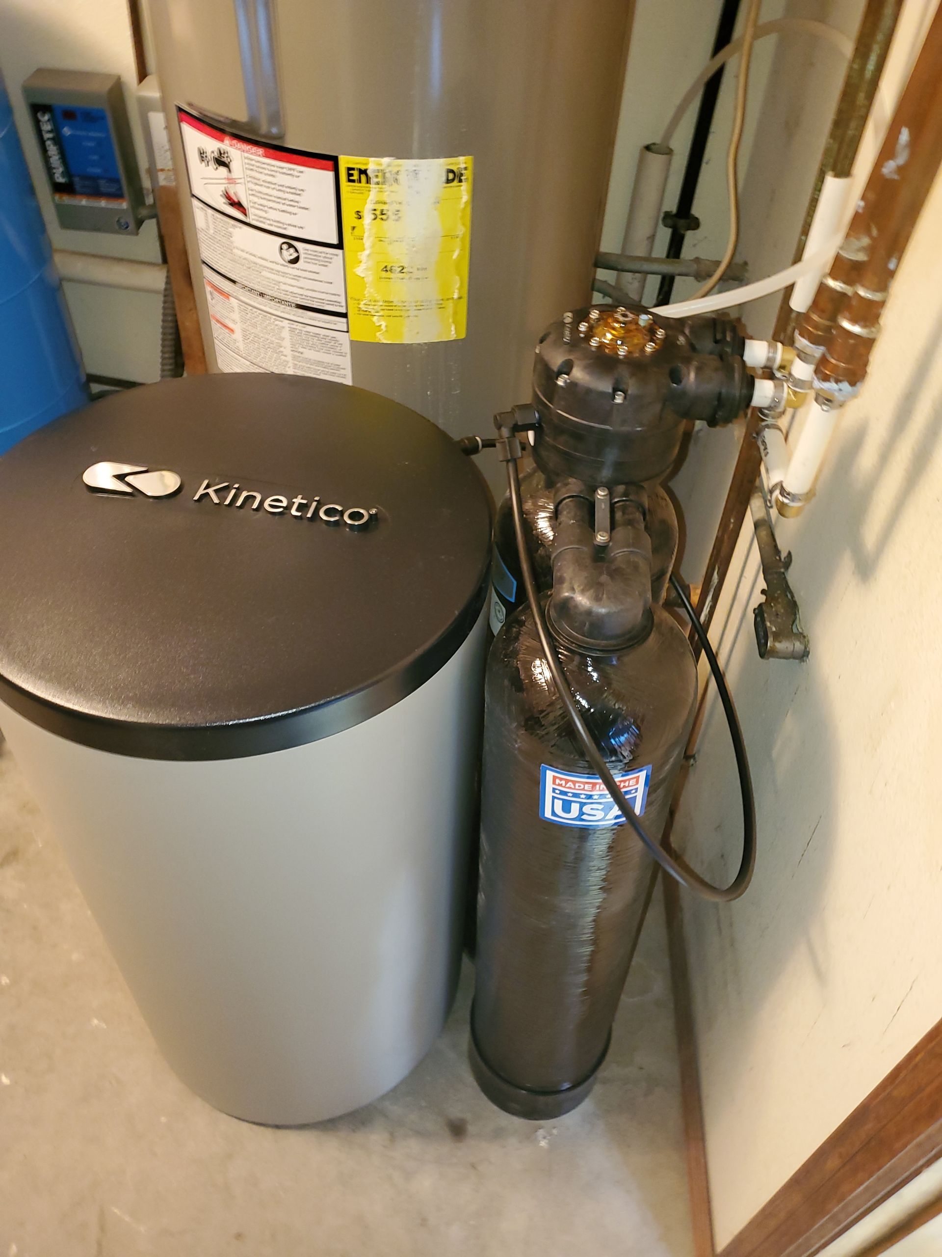 Water softener system beside a water heater in a utility room.