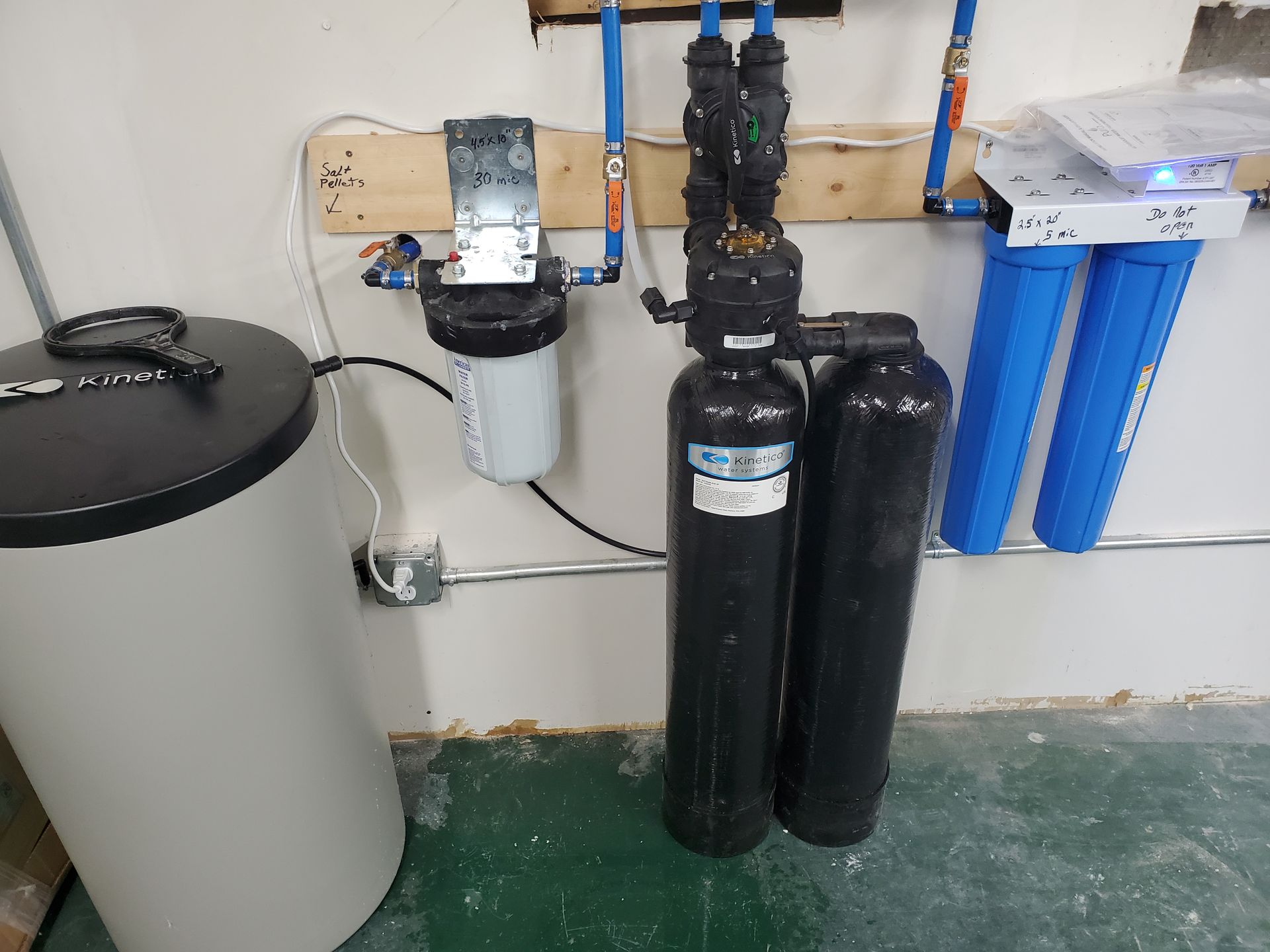 Water filtration system with various tanks, filters, and pipes in a utility room.