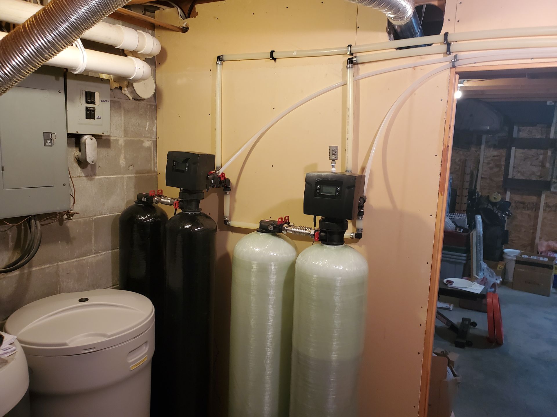 Water filtration system in basement. Includes tanks, control units, and plumbing on a wall.