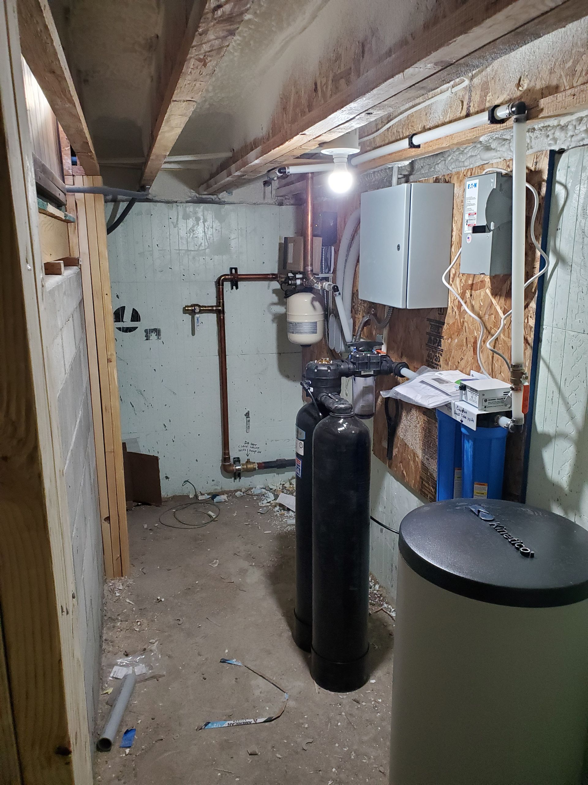 Basement water filtration system with tanks, pipes, and electrical components.
