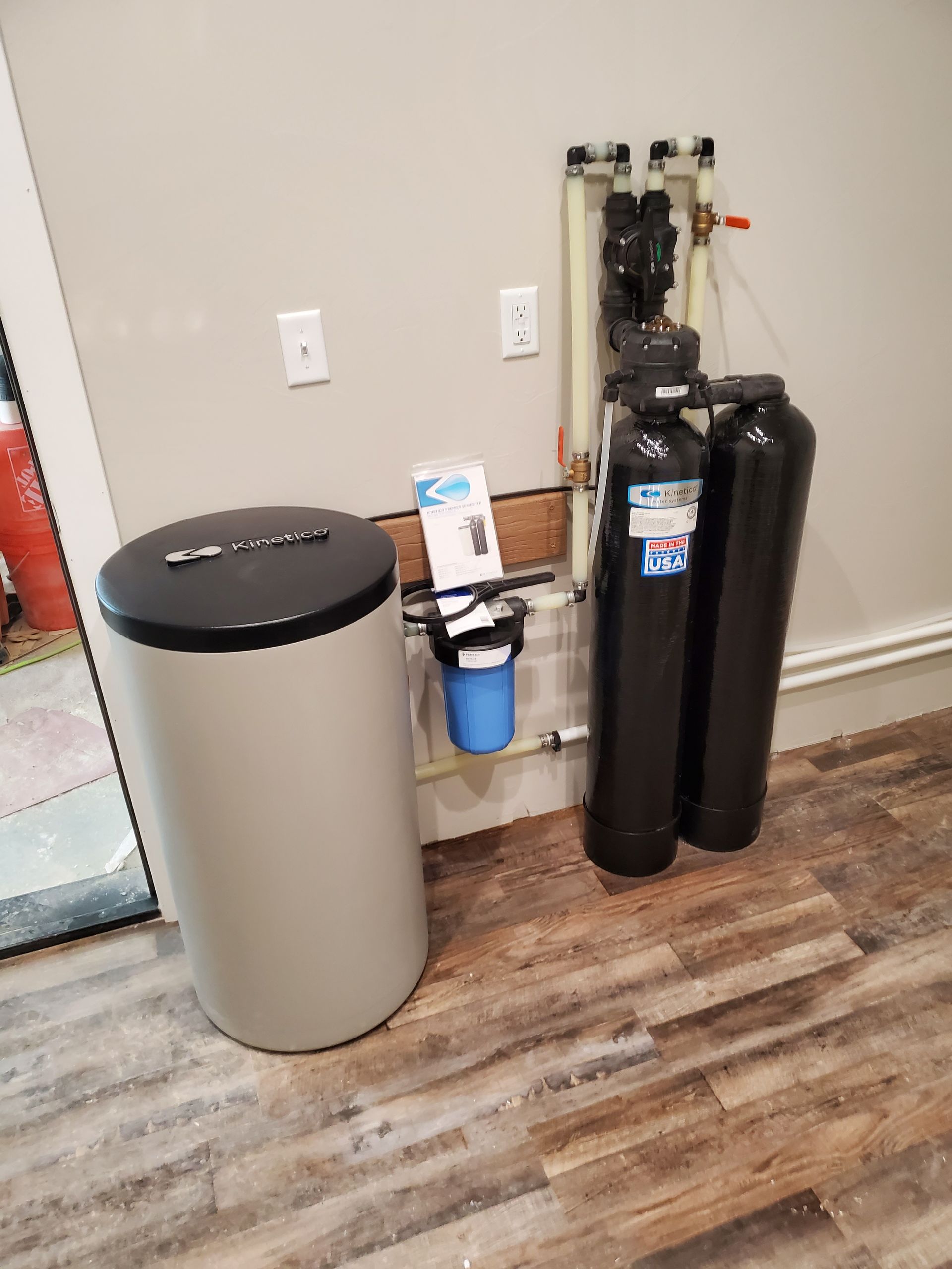 Water filtration system with tanks, and a softening unit against a wall.