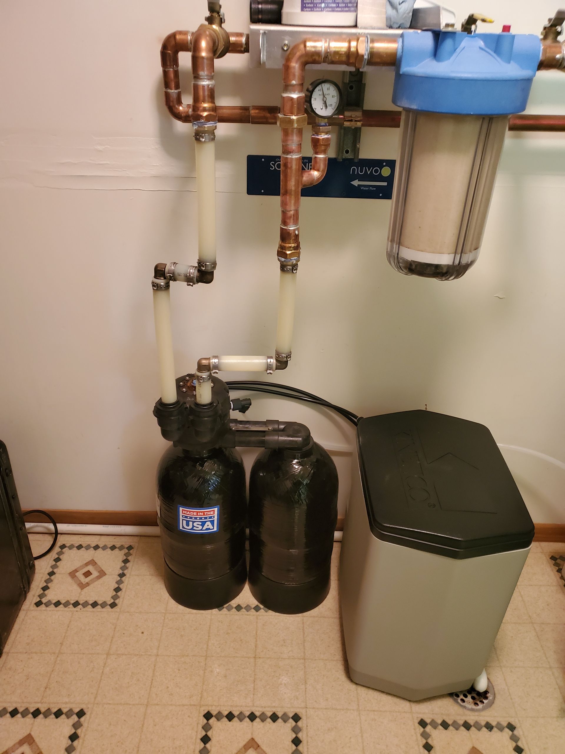 Plumbing system with copper pipes and water softener components in a utility room setting.