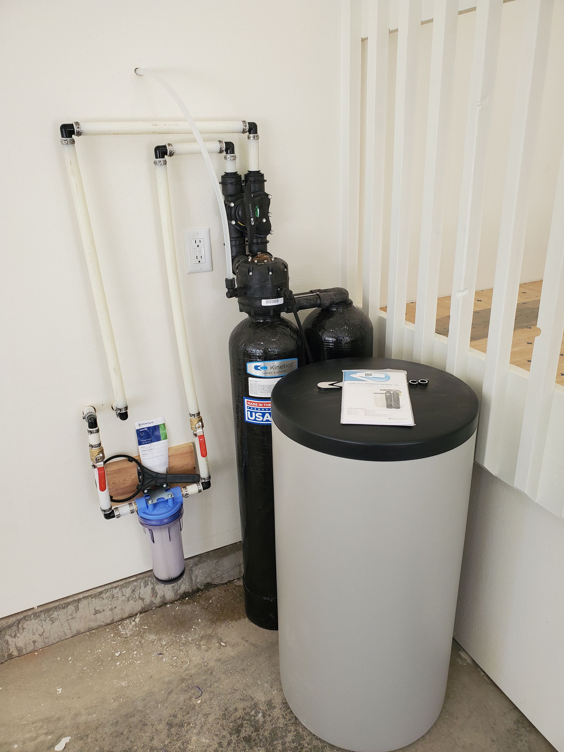 Water filtration system in a garage, including tanks, filters, and piping.