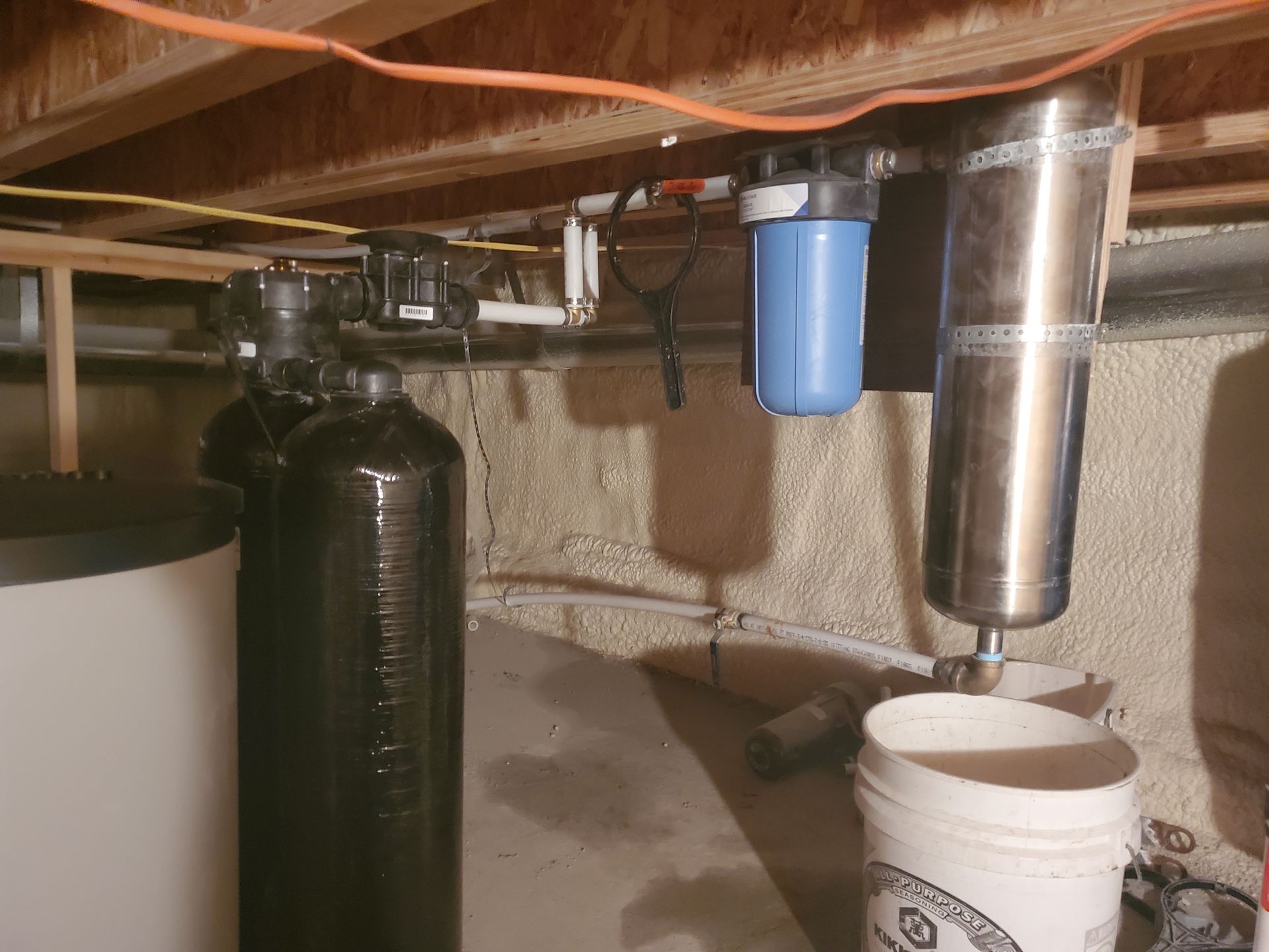 Water filtration system in basement, including tanks, filter housings, and plumbing.