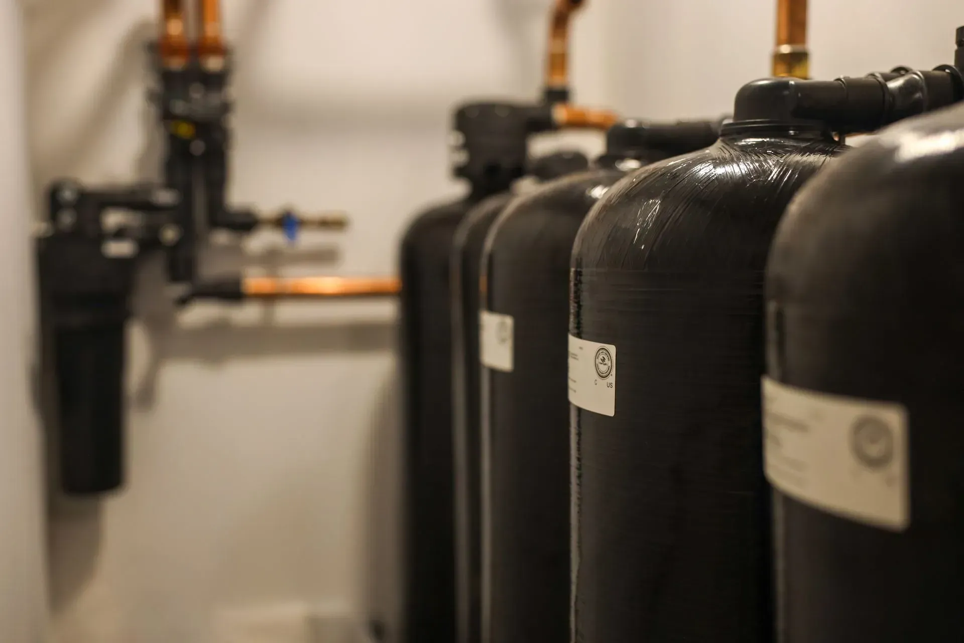 Electrician in a safety vest and hardhat, inspecting electrical panel.