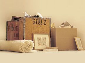 A rolled up rug and pictures around crates and packing boxes