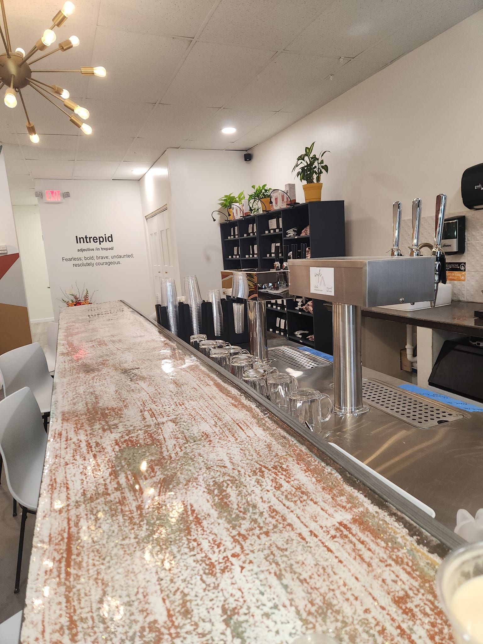 Modern café counter with silver taps, white speckled bar, shelves, and hanging starburst lights