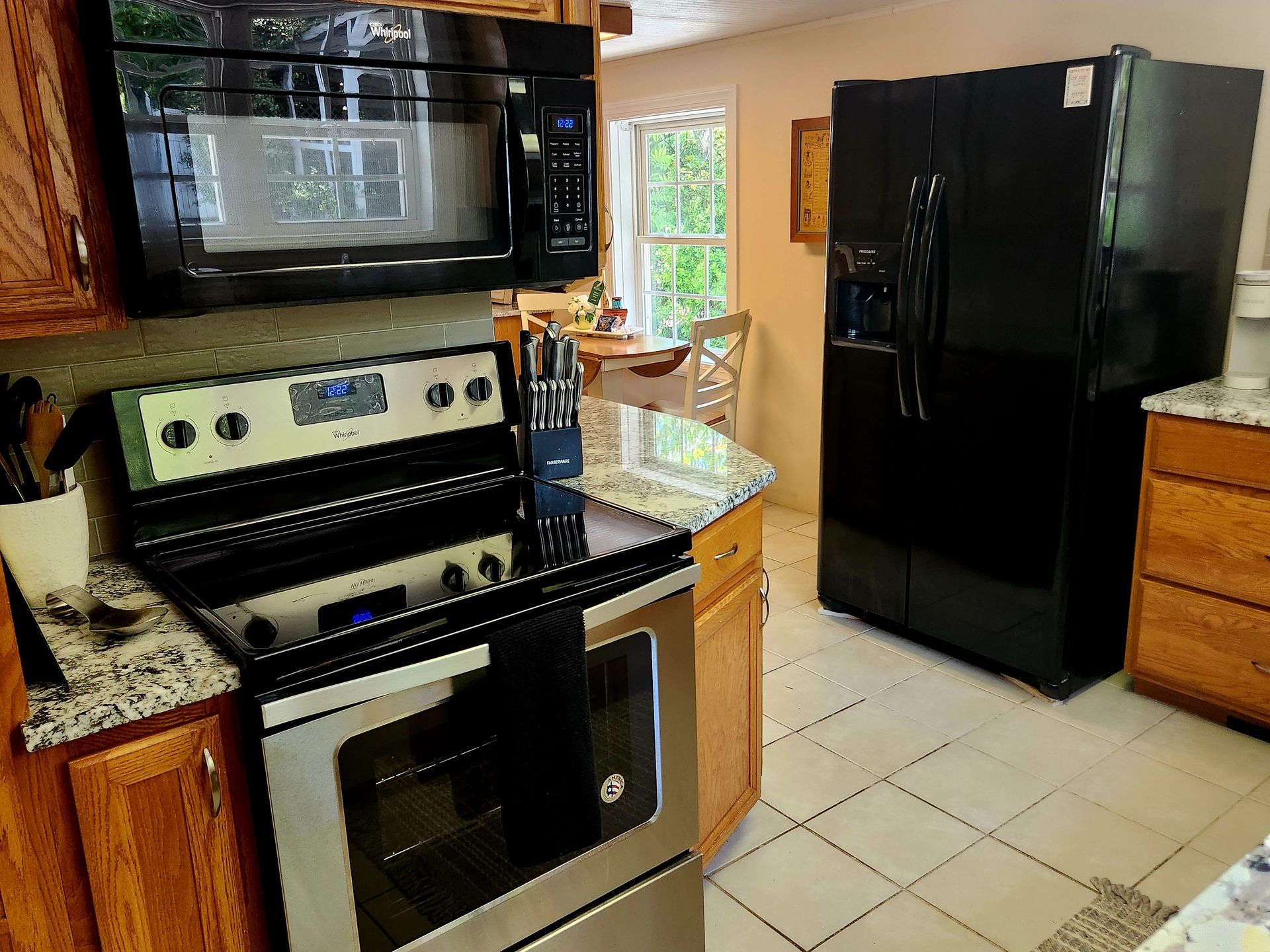 Kitchen with stainless steel appliances, black microwave and refrigerator.