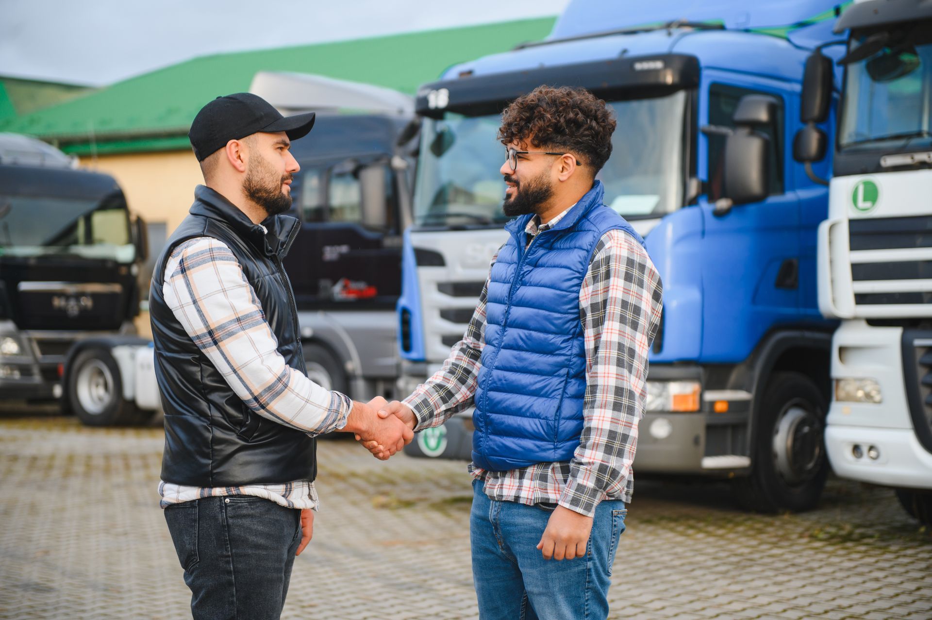 Truck drivers handshaking, completing a business agreement in a lot full of trucks.