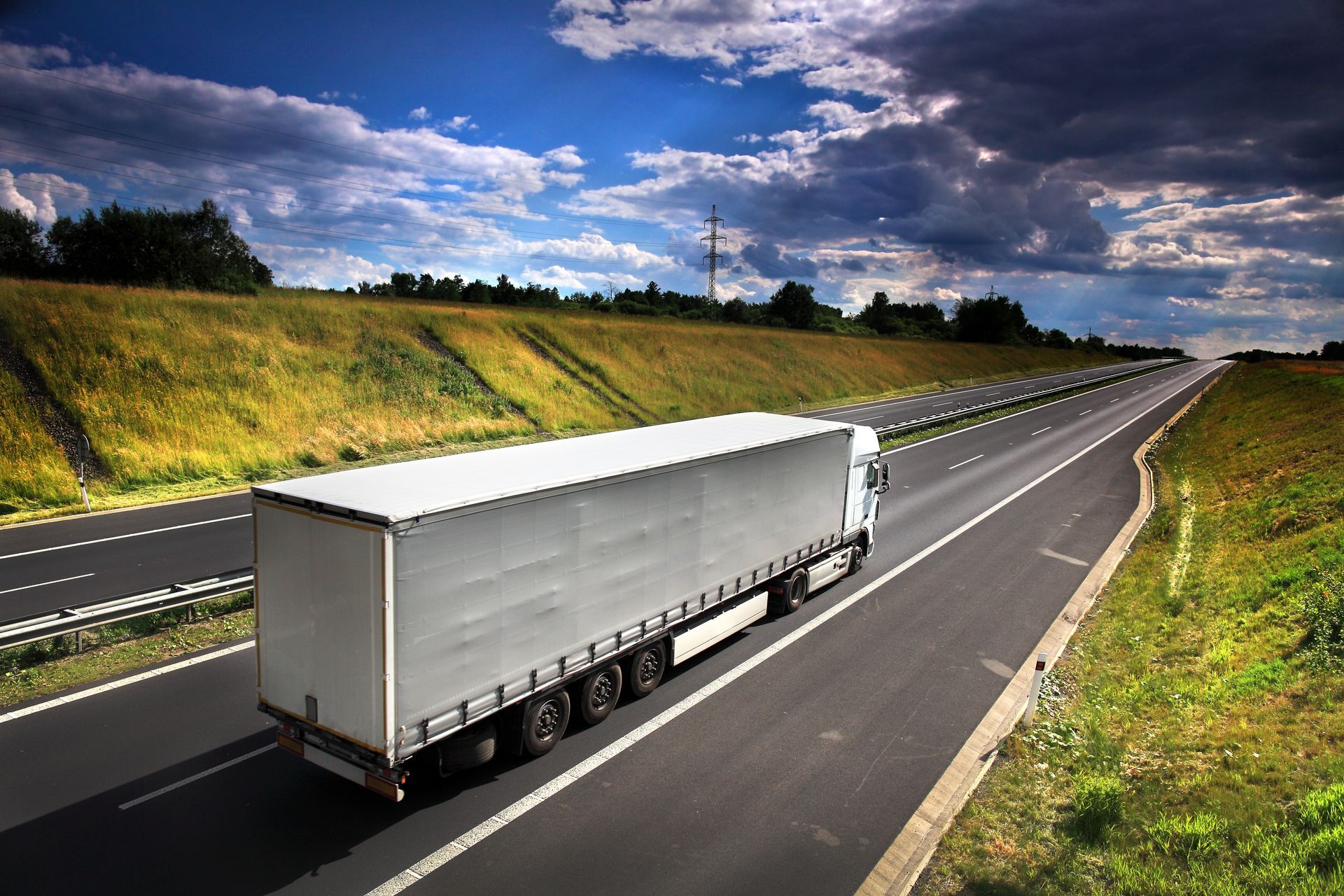 Truck on a road with green pastures surrounding it.