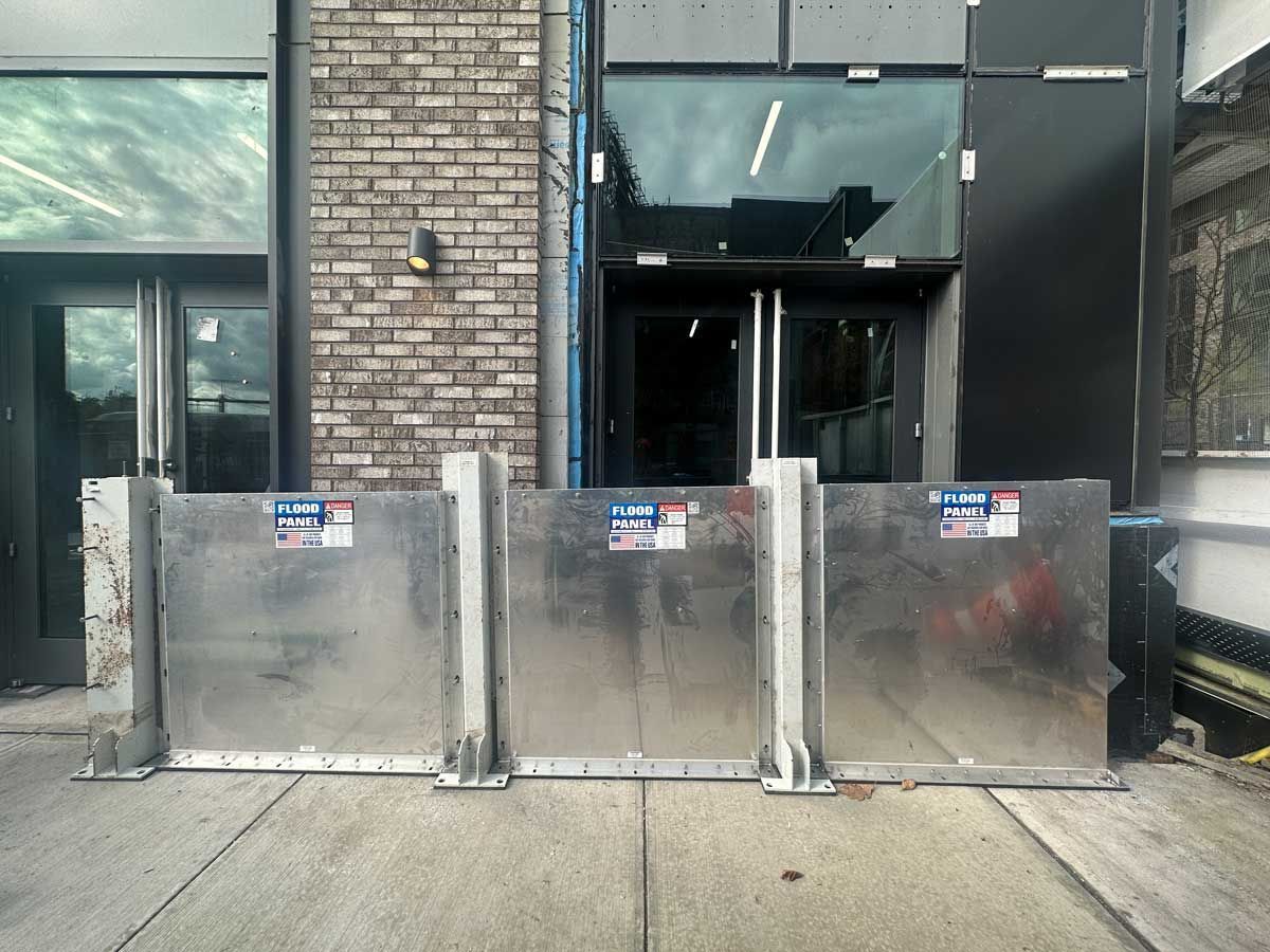 A row of metal barriers are sitting on the sidewalk in front of a building.