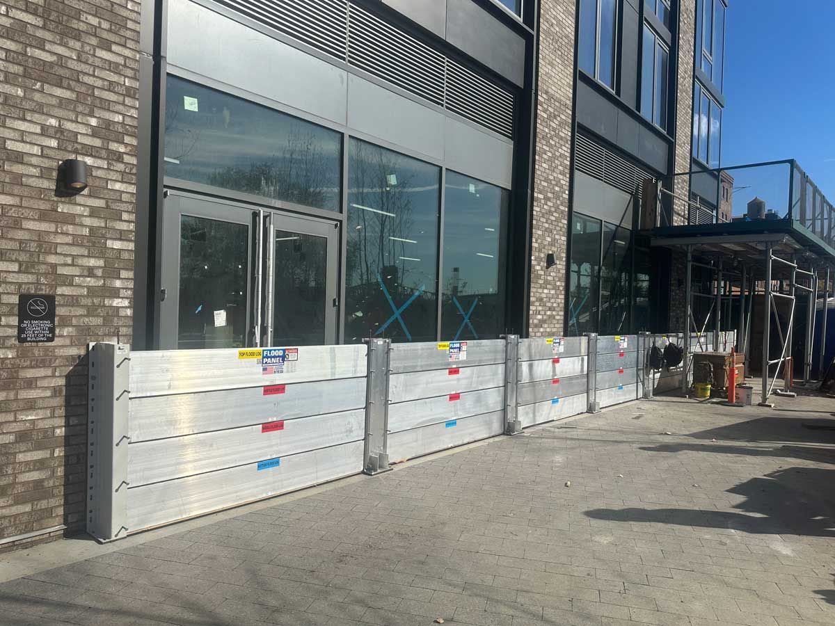 A building with a lot of windows and a lot of flood barriers in front of it.