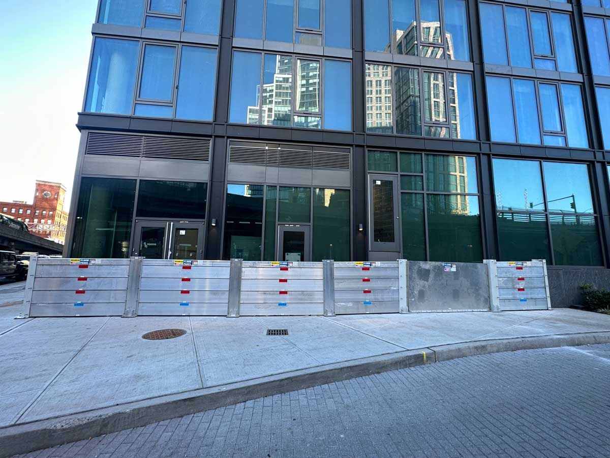 A building with a lot of windows and a lot of flood barriers in front of it.