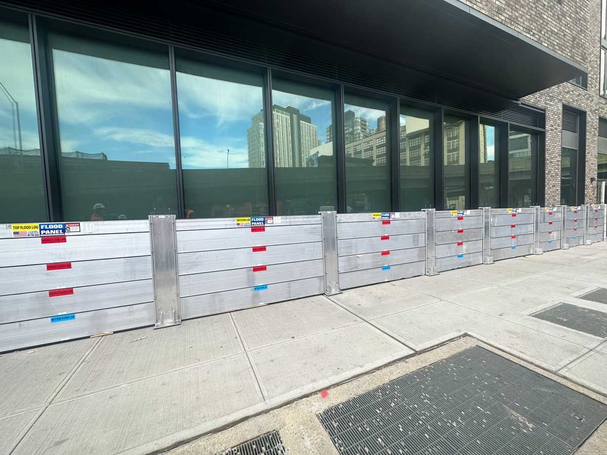 A row of flood barriers are sitting on the sidewalk in front of a building.