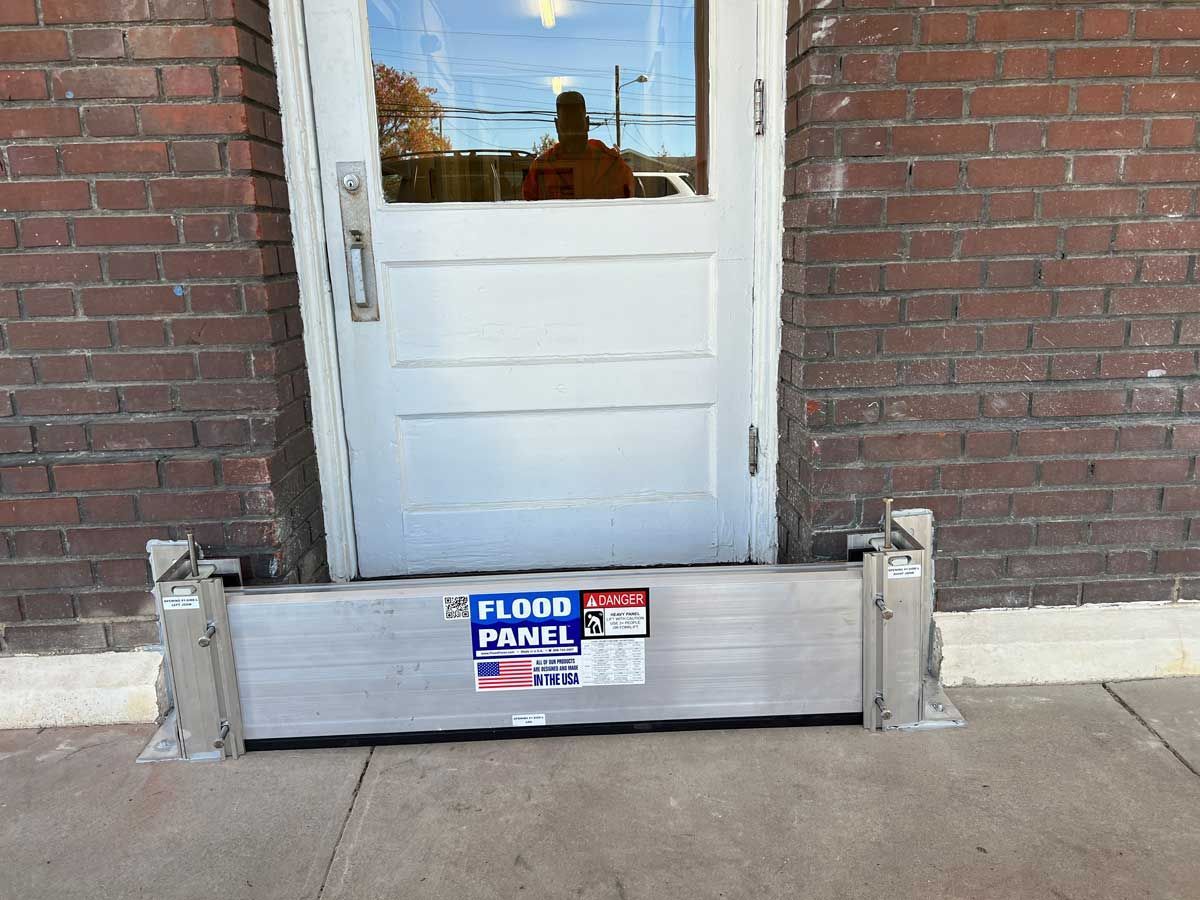 A flood barrier is sitting in front of a brick door.