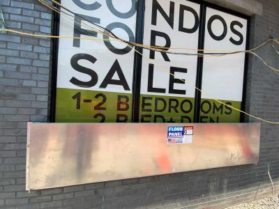 A condos for sale sign on a brick building