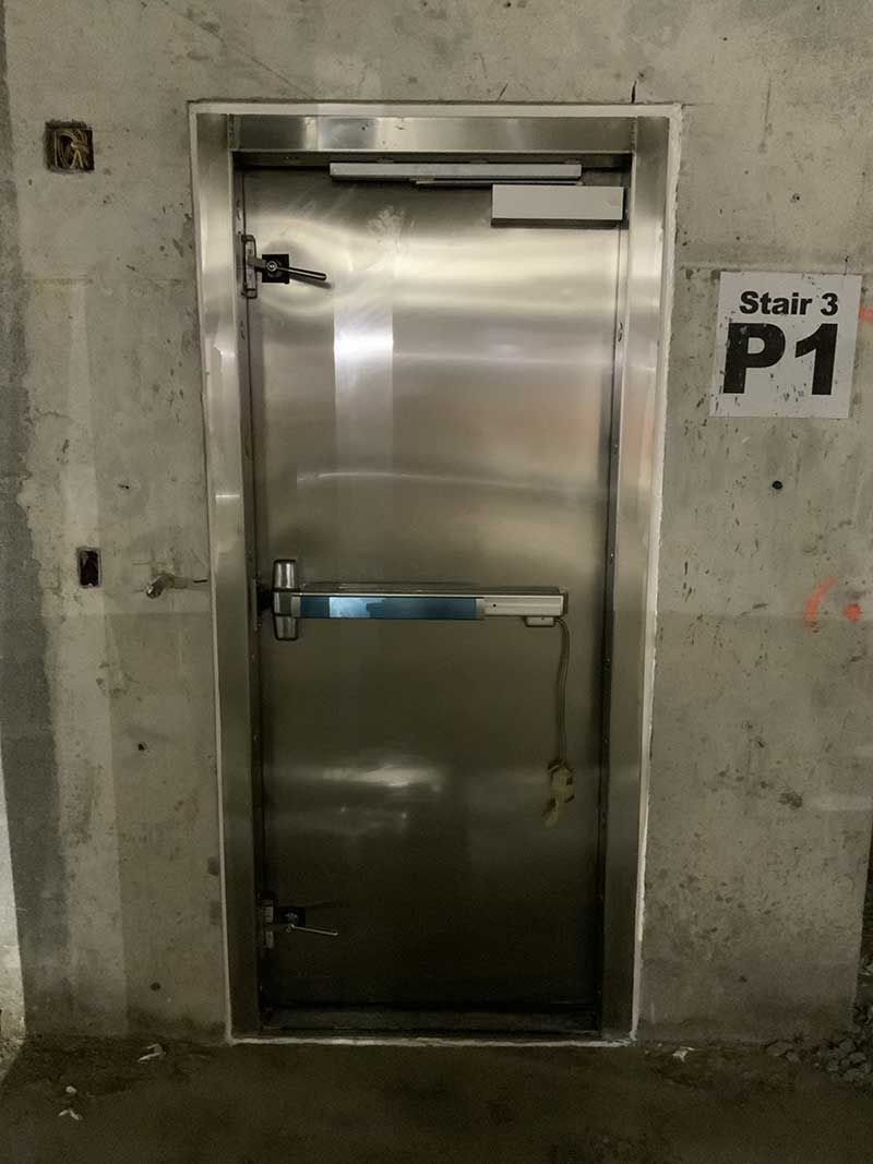 A stainless steel door with a sign on the wall.