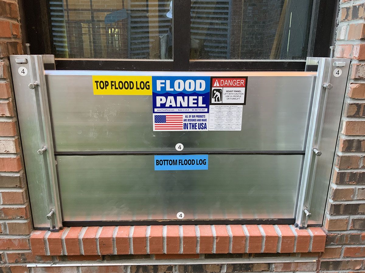 A flood panel is sitting on a brick wall next to a window.