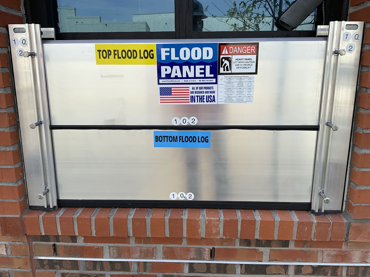 A top flood log flood panel is attached to a brick wall