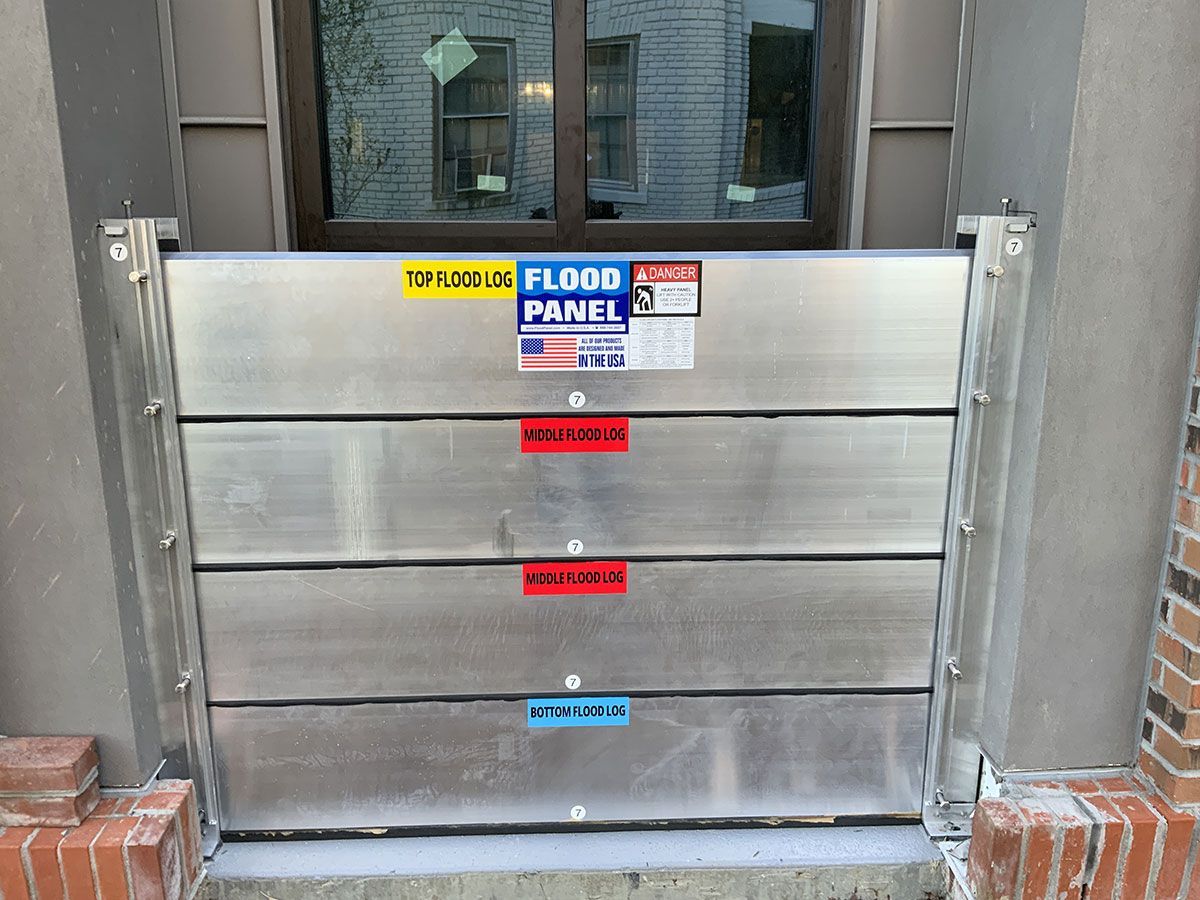A stainless steel flood barrier is sitting in front of a window.