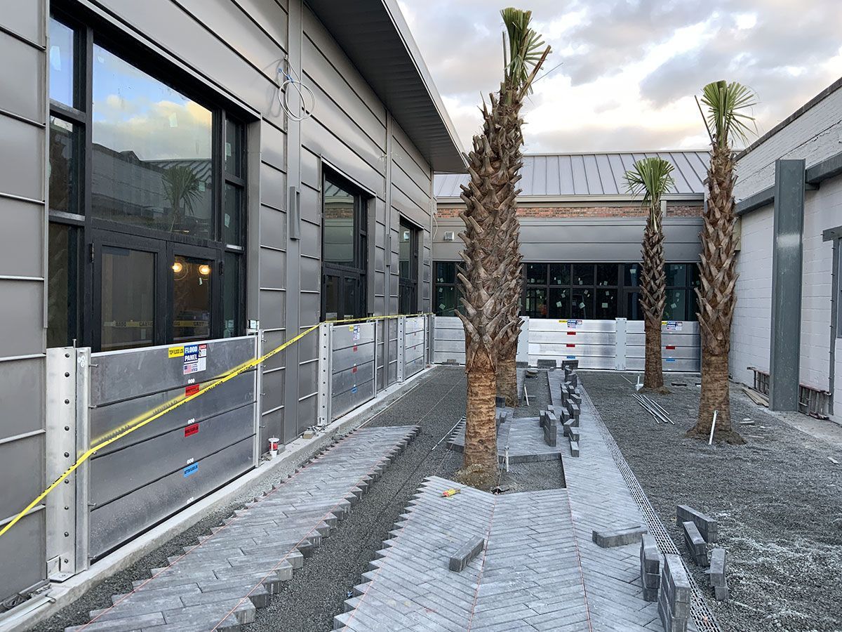 A building under construction with palm trees in front of it.