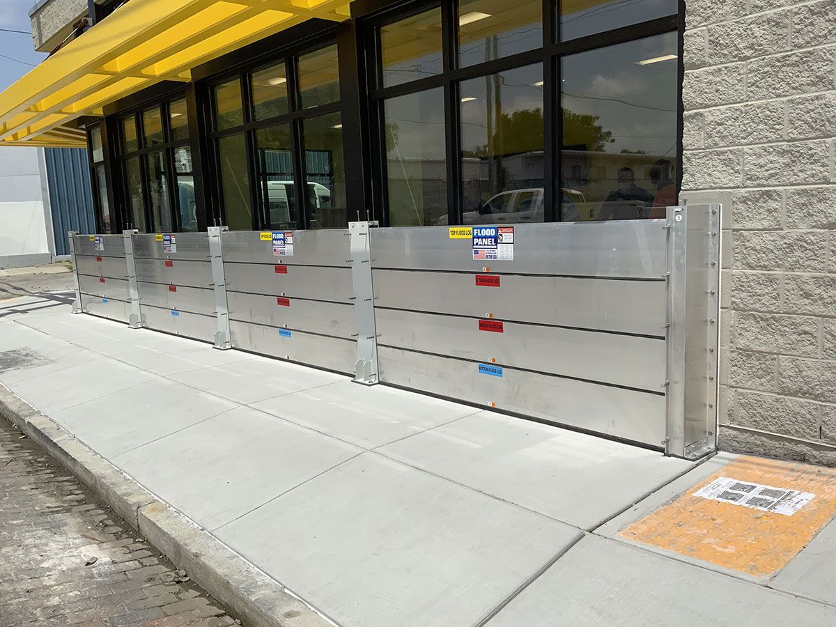 A row of aluminum flood barriers on the sidewalk in front of a building.