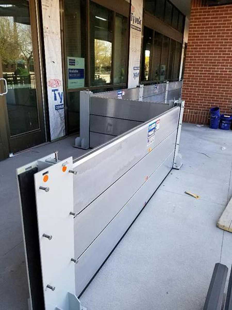 A flood barrier is sitting on the sidewalk in front of a building.