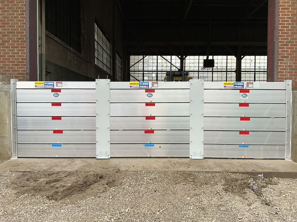 A row of aluminum flood barriers are sitting in front of a brick building.